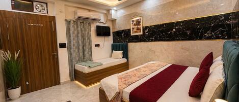 A modern hotel room with a bed, a desk, a ceiling fan, and a TV.