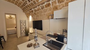 A modern kitchen with a stone arch, a sink, and a countertop. - Loft Aureo SicilyMyHome (Noto)