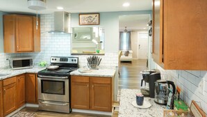A modern kitchen with wooden cabinets, stainless steel appliances, and a marble countertop.