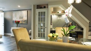 A dining area with a glass table, a vase with flowers, and a bowl of fruit.