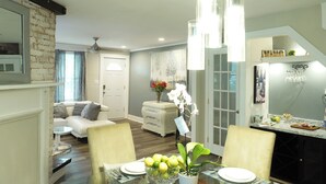 A modern kitchen with a dining area, featuring a white dining table, chairs, and a vase with flowers.
