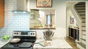 A kitchen with a stove, a sink, and a countertop with a knife block.