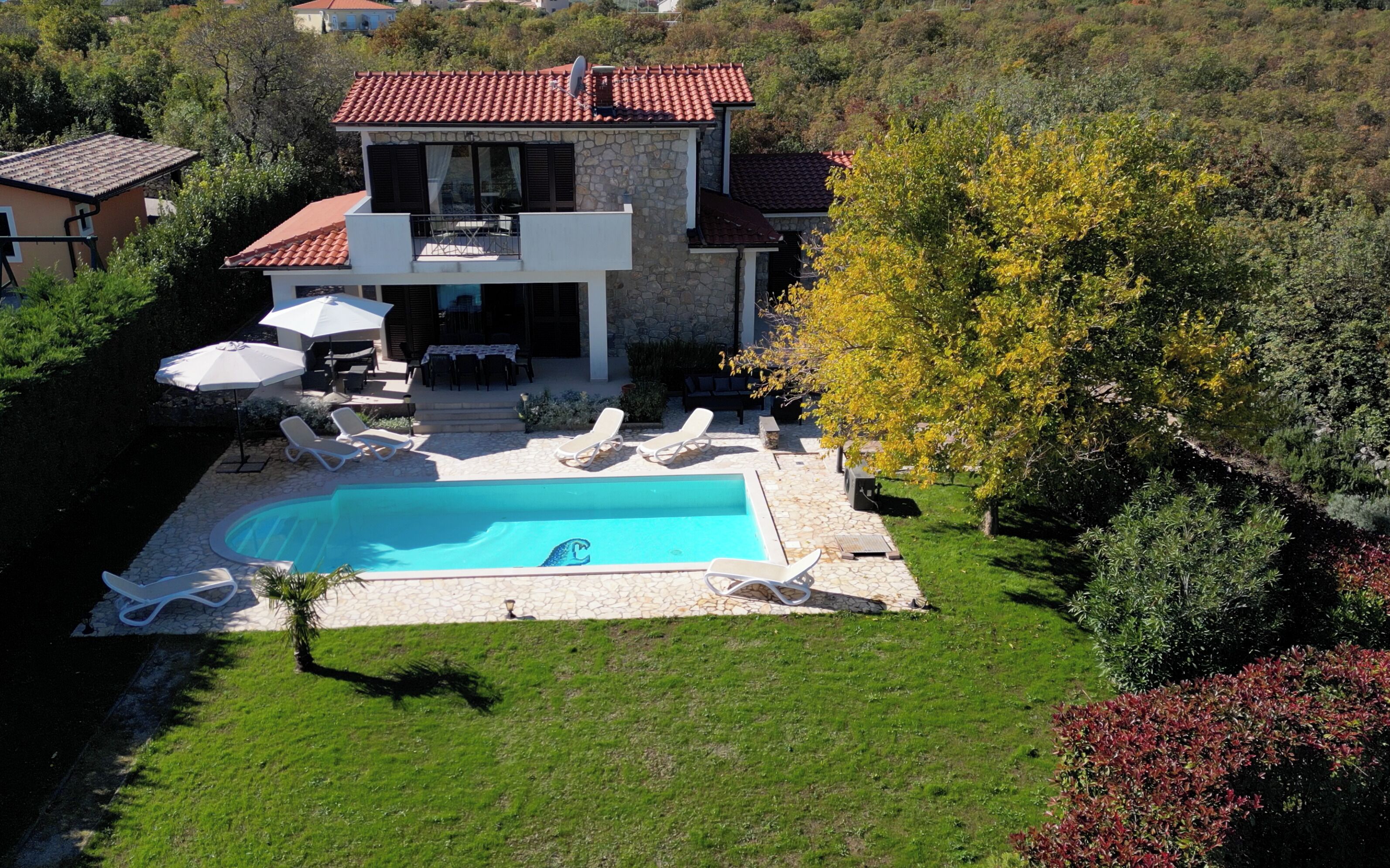 Une maison à deux étages avec une piscine, du mobilier d’extérieur et un jardin.