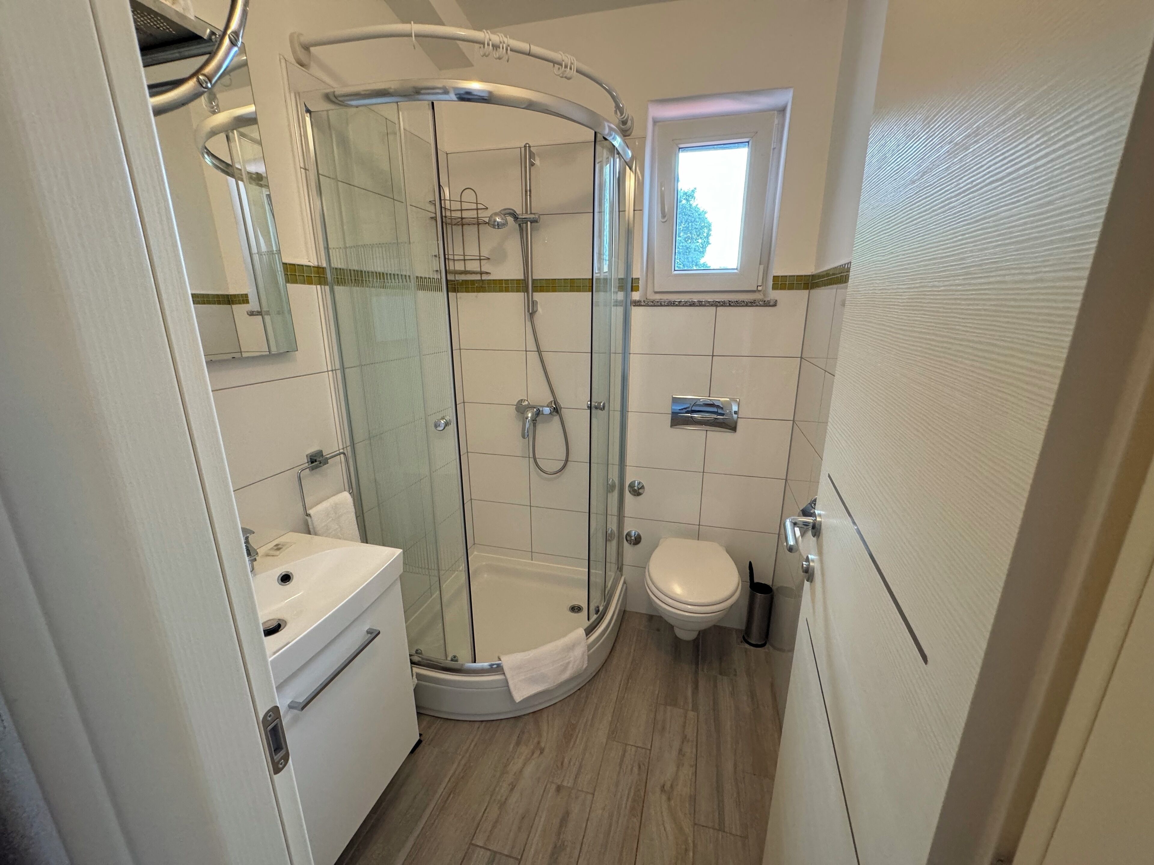 A compact bathroom with a glass-enclosed shower, a toilet, and a sink.