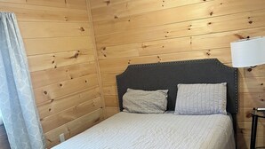 A wooden-paneled room with a bed, a lamp, and a curtain. - Charming cabin in Brushton NY. Unit 9 (Brushton)
