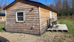 A small wooden cabin with a window, a door, and a small deck with a chair. - Charming cabin in Brushton NY. Unit 9 (Brushton)