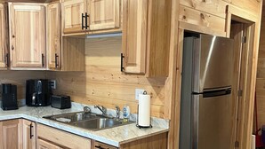 A wooden-paneled kitchen with a stainless steel refrigerator, a coffee maker, and a sink. - Charming cabin in Brushton NY. Unit 9 (Brushton)