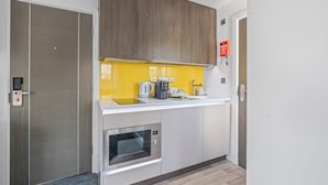 A modern kitchen with a built-in microwave, a coffee maker, and a kettle on the countertop. - New House Serviced Apartments (Coventry)