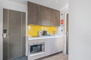 A modern kitchen with a built-in microwave, a coffee maker, and a kettle on the countertop.