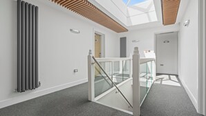 A modern interior with a skylight, a glass railing, and a radiator. - New House Serviced Apartments (Coventry)