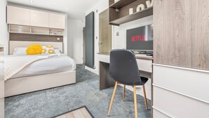 A modern bedroom with a bed, a desk, a chair, and a TV displaying 'NETFLIX'. - Contemporary Comfort Steps from Ricoh Arena (Coventry)