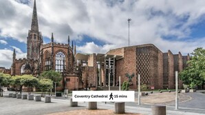 Coventry Cathedral with a modern extension, a prominent spire, and a clear sky. - Contemporary Comfort Steps from Ricoh Arena (Coventry)