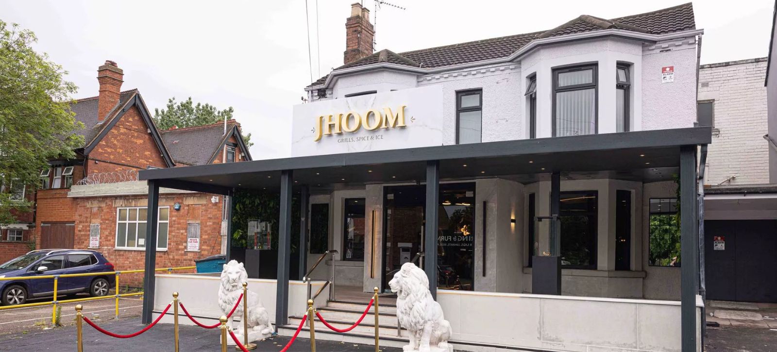 A restaurant named "Jhoom" with a covered entrance and two white lion statues.