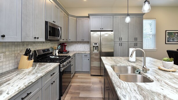 A modern kitchen with grey cabinets, stainless steel appliances, a marble countertop, and pendant lighting. - Downtown Tomball-Built in 2025, King Bed, Sleeps 6 (Tomball)