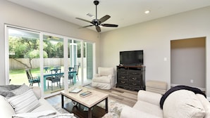 A living room with a sofa, armchair, coffee table, and a television. - Downtown Tomball-Built in 2025, King Bed, Sleeps 6 (Tomball)
