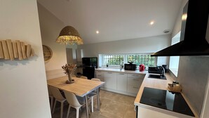 A modern kitchen with a dining area, featuring a black refrigerator, a microwave, and a coffee maker. - Le Logis des Écuries **** - Charming rooms with swimming pool - Côte Roannaise (Renaison)