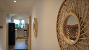 A hallway leading to a kitchen with a modern design, including a black refrigerator and a window with a view of greenery. - Le Logis des Écuries **** - Charming rooms with swimming pool - Côte Roannaise (Renaison)