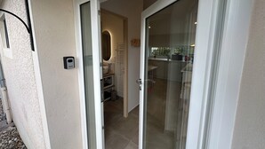 A modern bathroom with a glass door leading to a kitchen area. - Le Logis des Écuries **** - Charming rooms with swimming pool - Côte Roannaise (Renaison)