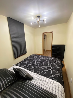 Un dormitorio con cama, cómoda, espejo y lámpara en el techo.