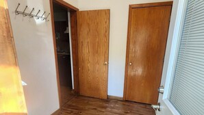 Una habitación con suelo de madera, paredes blancas y dos puertas de madera.