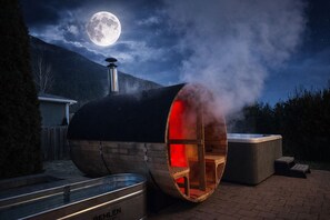 A sauna with a large cylindrical structure, a visible chimney, and a wooden bench inside. - Premier host-4BR/HotTub/Sauna/Massage Chairs (Revelstoke)