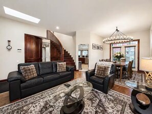 A spacious living area with a black leather sofa, a glass coffee table, and a patterned rug.