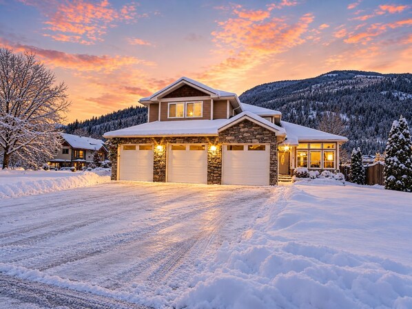 A two-story house with a stone facade, a garage, and a driveway. - Premier host-4BR/HotTub/Sauna/Massage Chairs (Revelstoke)