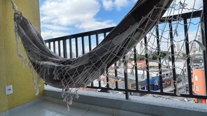 Een hangmat op een balkon met uitzicht op de stad.