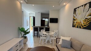 Una sala moderna con sofá, mesa de centro y zona de comedor con sillas.