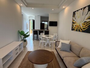 Un salon moderne avec un canapé, une table basse et un coin repas avec des chaises.