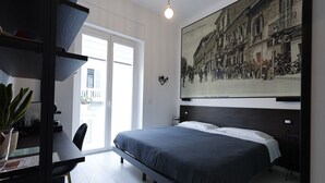 A modern bedroom with a bed, a desk, and a large window. - OkHome (Pescara)
