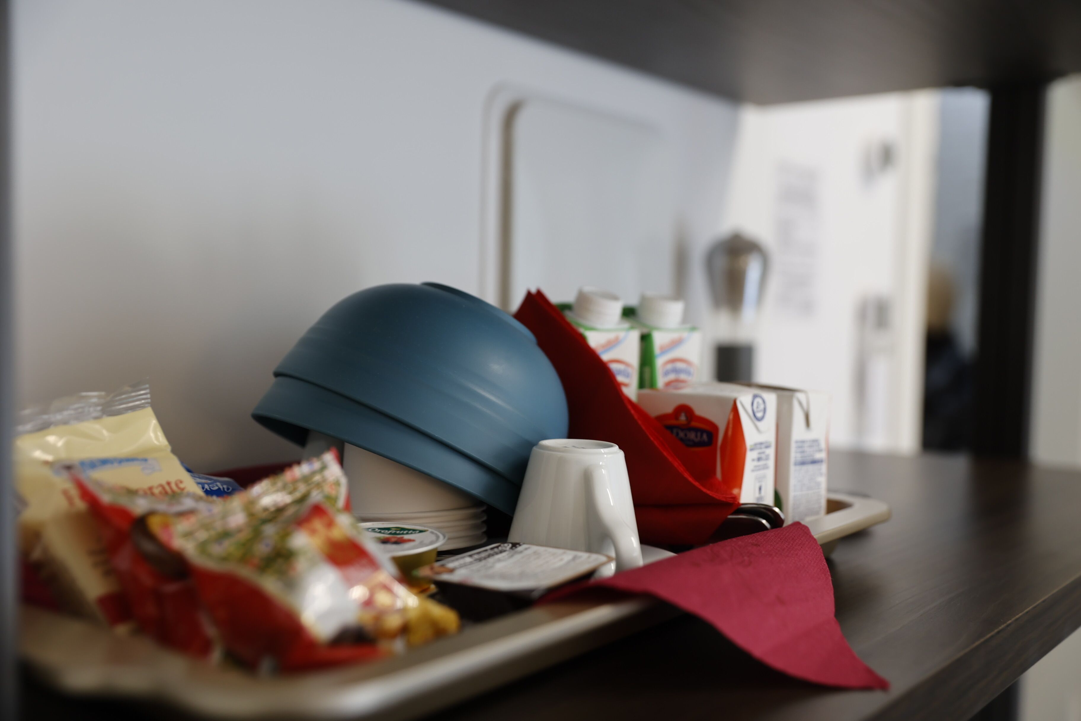 A tray with a blue helmet, a white mug, a red napkin, and various food items.