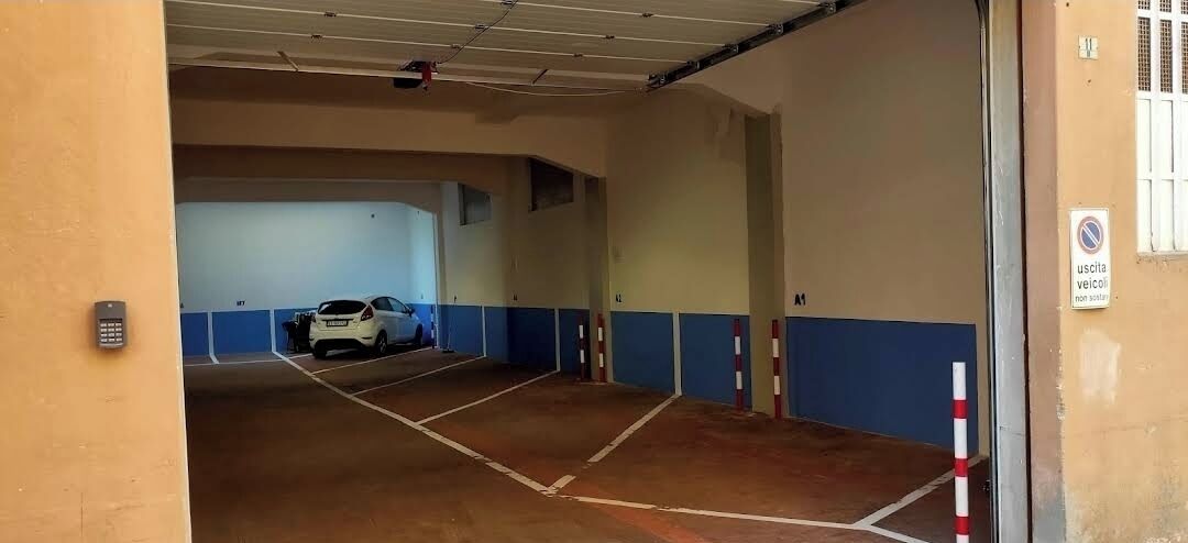 A parking garage with multiple levels, marked parking spaces, and a white car parked in one of the spaces.