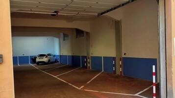A parking garage with multiple levels, marked parking spaces, and a white car parked in one of the spaces.