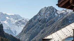 Un chalet de montagne avec un toit en pente et une vue sur les sommets enneigés.