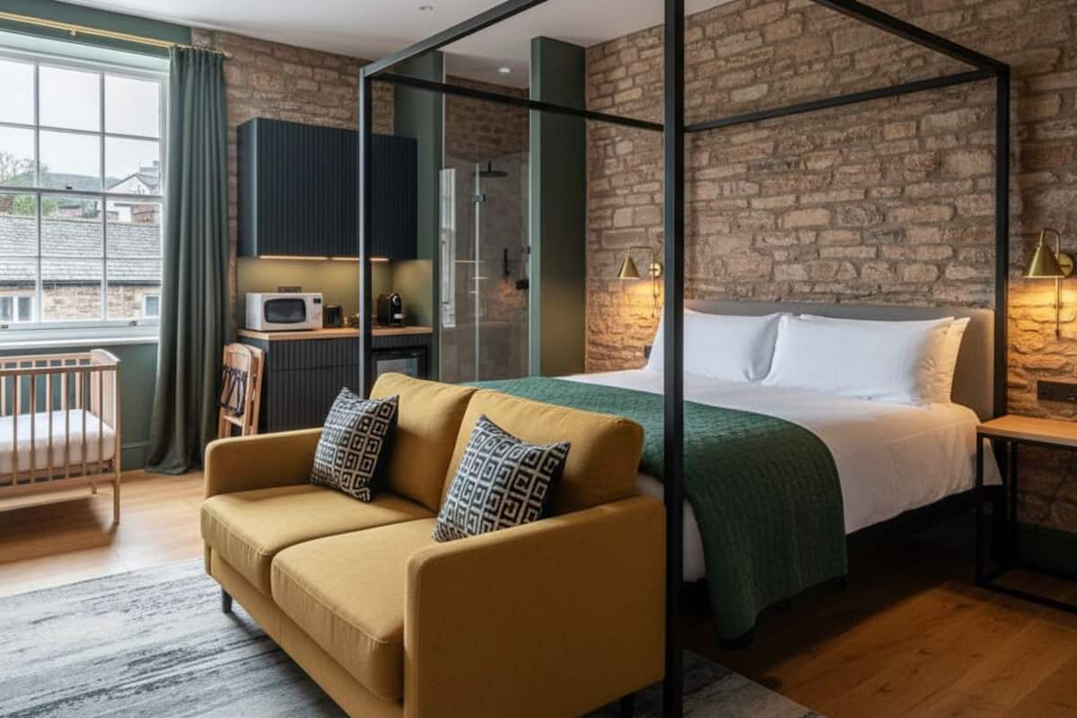Un dormitorio moderno con cama con dosel, un sofá, una cuna y una kitchenette.