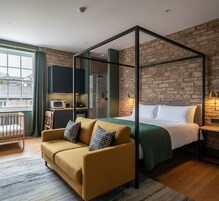 Un dormitorio moderno con cama con dosel, un sofá, una cuna y una kitchenette.