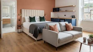 A modern bedroom with a bed, a grey sofa, and a small table. - The Civic Hall - Wayth Hotels (Hebden Bridge)