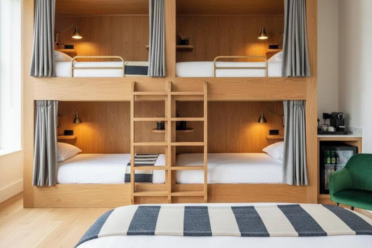 Habitación con literas, dos mesitas de noche y una silla verde.