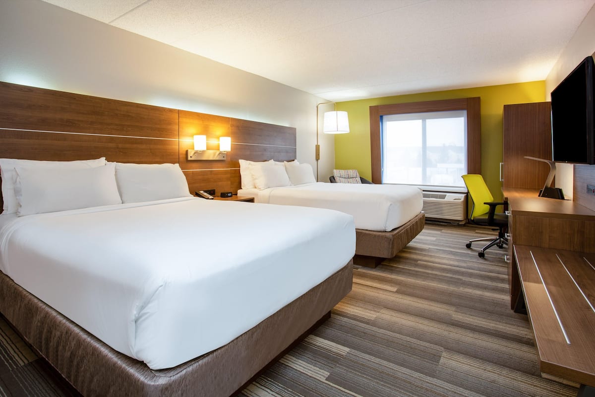 Une chambre d’hôtel avec deux lits, un bureau, une chaise et un téléviseur.