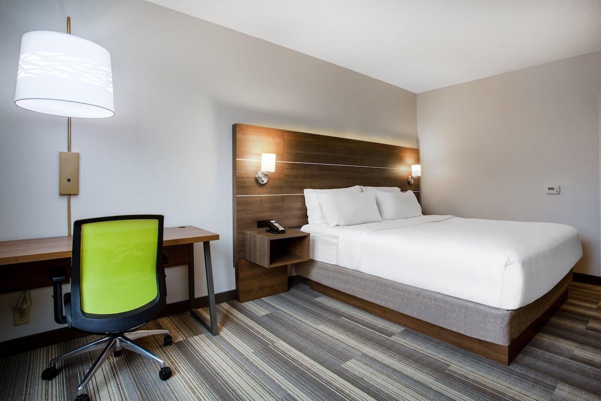 Une chambre d’hôtel avec un lit, un bureau, une chaise et une lampe.