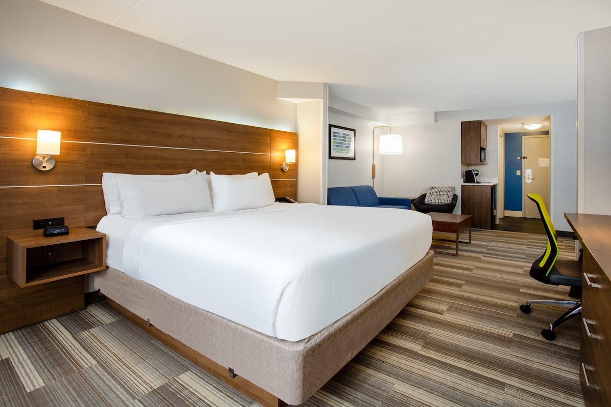 Une chambre d’hôtel avec un grand lit, des tables de chevet, un bureau, une chaise et une petite kitchenette.