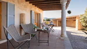 An outdoor patio with wicker chairs, a table, and a hanging plant.
