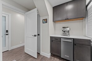 A modern kitchen with a dishwasher, a coffee machine, and a cabinet above the counter.