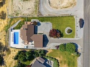 Vista aerea di una proprietà residenziale con piscina, vialetto e prato curato.