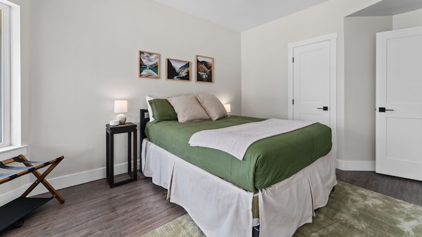 A bedroom with a bed, a nightstand, a lamp, a ceiling fan, and three framed pictures on the wall. - Summit Ridge - Lake Chelan & Mountain Views (Manson)