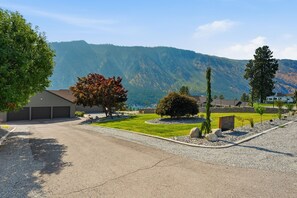 A residential area with a house, a garage, a well-maintained lawn, and a mountain in the background.