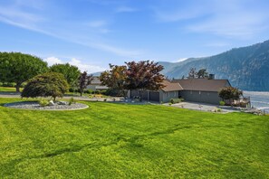 A residential property with a well-maintained lawn, a detached house, and a mountain backdrop.