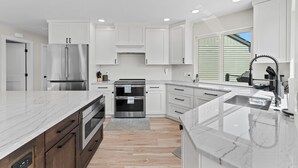 A modern kitchen with white cabinetry, stainless steel appliances, and a marble countertop. - Summit Ridge - Lake Chelan & Mountain Views (Manson)