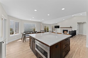 A spacious kitchen with a large island, built-in oven, and a fireplace.